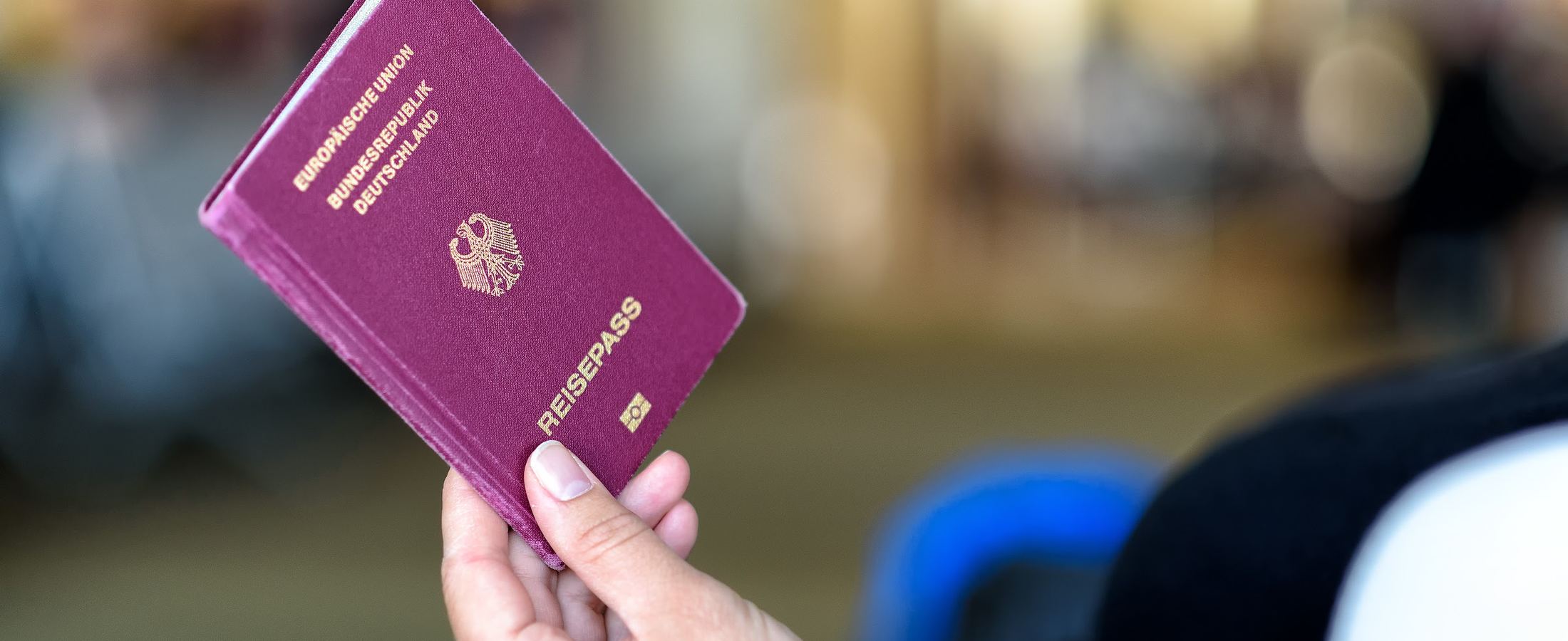 Pessoa segurando um passaporte alemão no saguão de um aeroporto